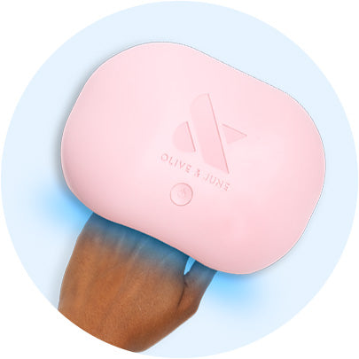 Hand under a pink Olive and June LED nail lamp curing gel polish with soft blue light glow