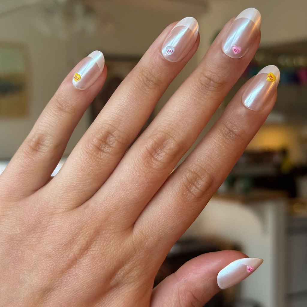 Hand showing Puffy Chrome Candy Heart French - Press On | Medium | Oval nails with 3D candy heart details indoors