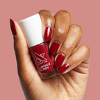 Hand with Brick polish showing deep red glossy manicure on medium skin against muted pink background