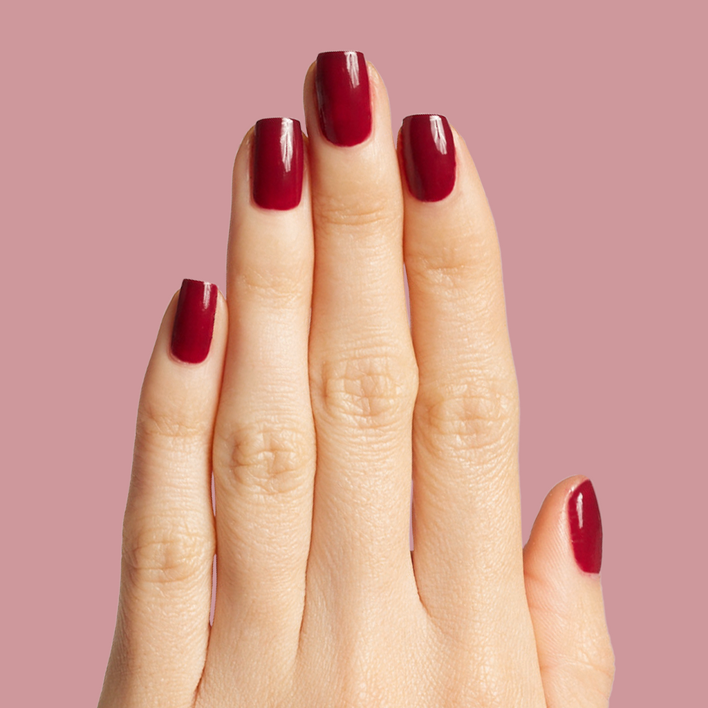 Hand with glossy Cabernet gel polish in dark plummy wine red for a rich, elegant at-home manicure look