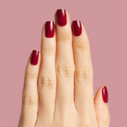 Hand with glossy Cabernet gel polish in dark plummy wine red for a rich, elegant at-home manicure look