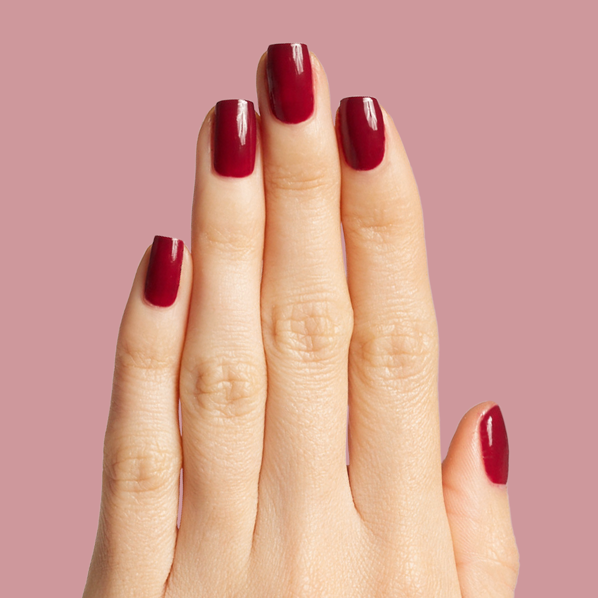 Hand with glossy Cabernet gel polish in dark plummy wine red for a rich, elegant at-home manicure look