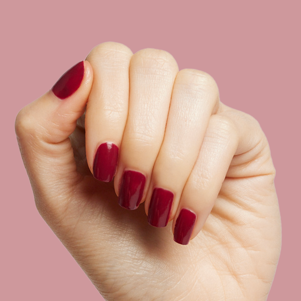 Hand with glossy Cabernet gel polish in dark plummy wine red for a rich, long-lasting at-home manicure look