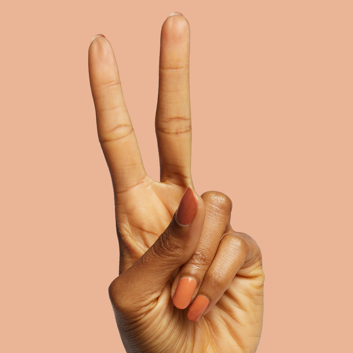 Hand showing peace sign with Canyon warm desert orange gel polish for easy at-home manicure and mani options