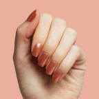 Hand showing Penny polish in shiny copper metallic manicure on light skin with peach background