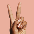 Hand with Penny showing a shiny copper metallic manicure on medium skin against a peach background