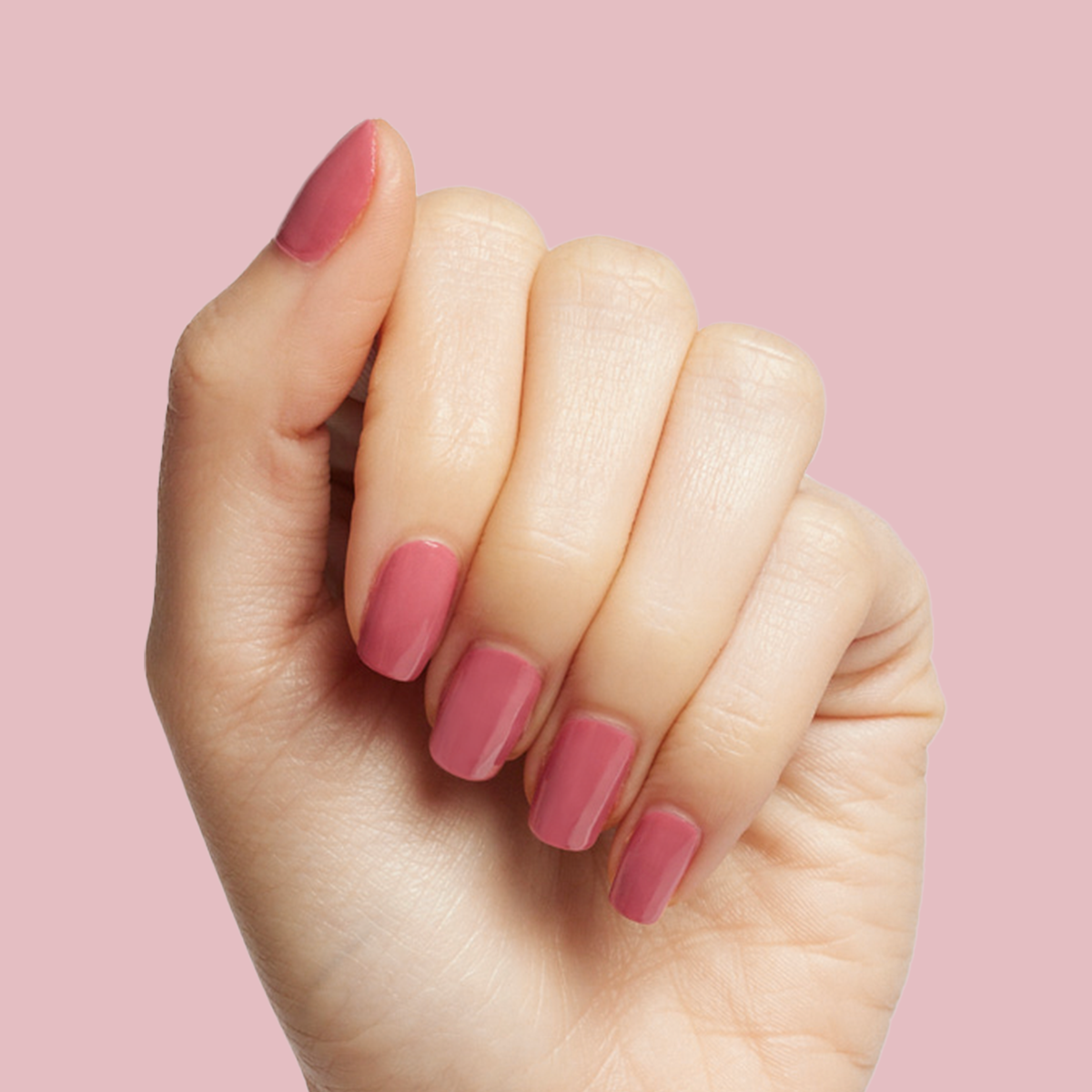 Hand showing nails painted with Primrose gel polish in warm rosy pink for a soft at-home manicure look