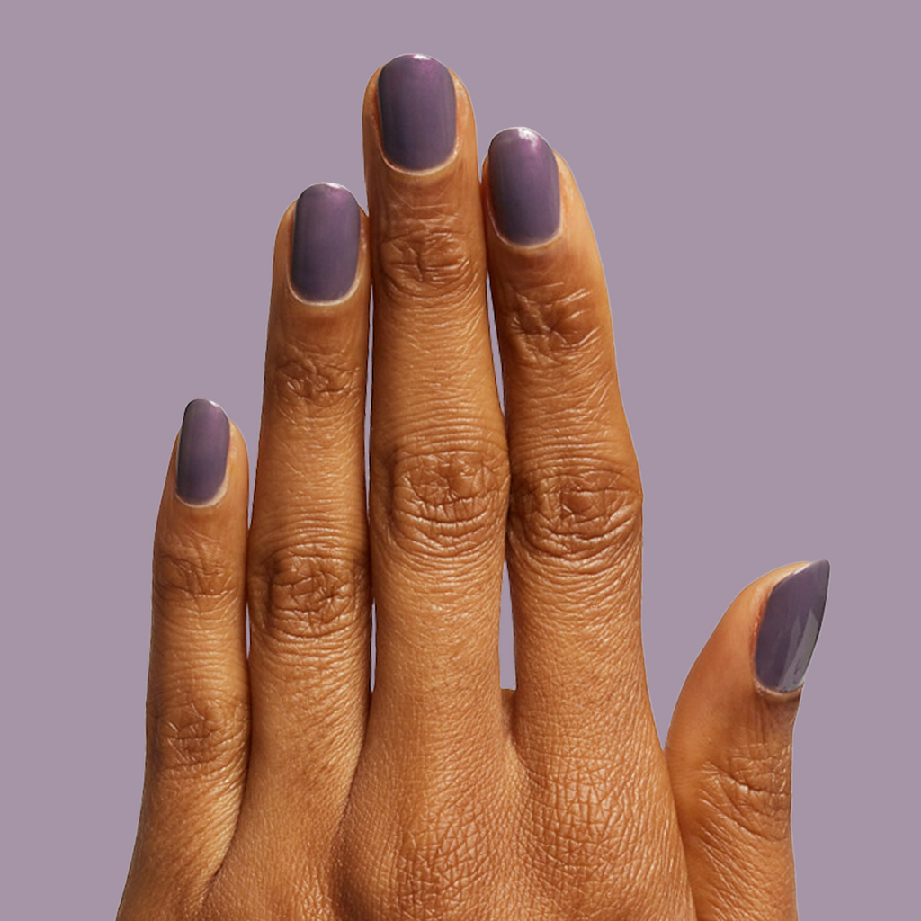 Hand showing Twilight gel polish in a smooth, iridescent violet manicure on medium skin tone against a soft purple background