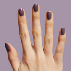 Hand showing Twilight gel polish in a glossy iridescent violet manicure on light skin against a muted purple background