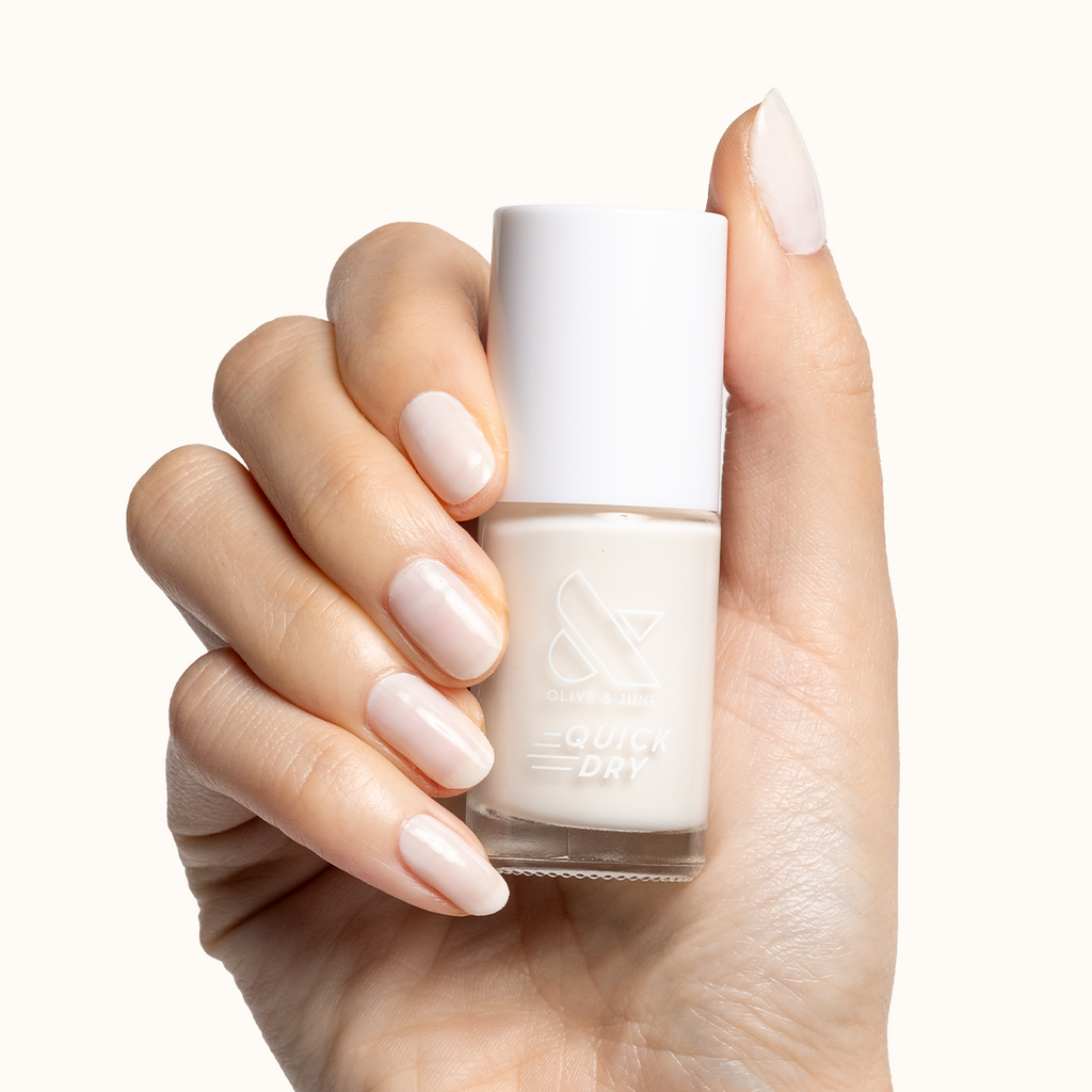 Hand holding Buttercream nail polish bottle with sheer milky white polish on natural nails for an elegant mani look