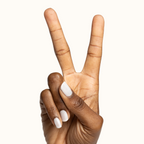 Hand showing two fingers with Buttercream sheer milky white polish on natural nails for a clean manicure look