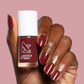 Saucy quick dry nail polish shown on hand with deep red shimmer mani against soft pink background
