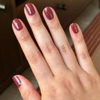 Saucy deep red quick dry gel polish shown on natural short nails with soft indoor lighting background