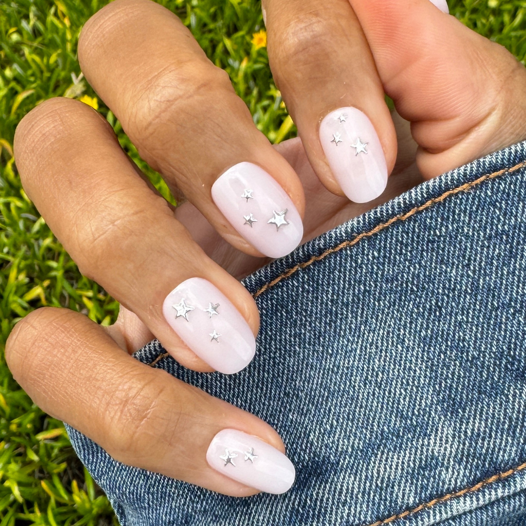 Soft Silver Foil Stars - Press-On | Short | Round showing hand with short round nails and 3D silver star accents outdoors