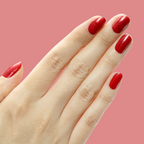 Hand with short nails painted in shimmery berry red gel polish Splash of Cran against a pink background