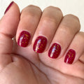 The Stardust Effect Top Coat adding reflective flake sparkle over glossy deep red polish for a bright manicure finish thumbnail