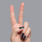 Hand with short nails painted in glossy Inkling gel polish showing a sleek quick dry mani on gray background