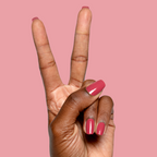 Hand with natural nails painted in glossy Roar quick dry gel polish showing confident manicure on pink background