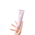 Hand with lilac manicure holding pink tube of HAND TREATMENT cream for hydration and skin renewal on white background