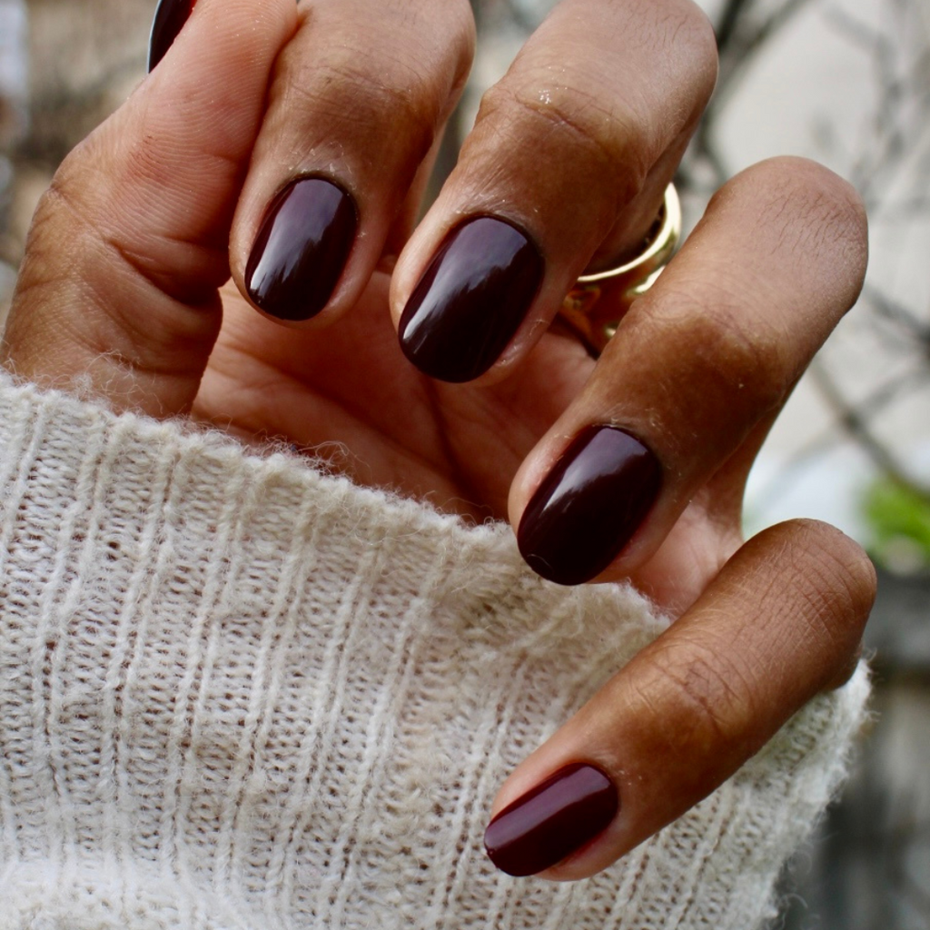 Vineyard | Short | Round - Tab Press-On showing hand with deep wine red glossy false nails and gold rings in natural light
