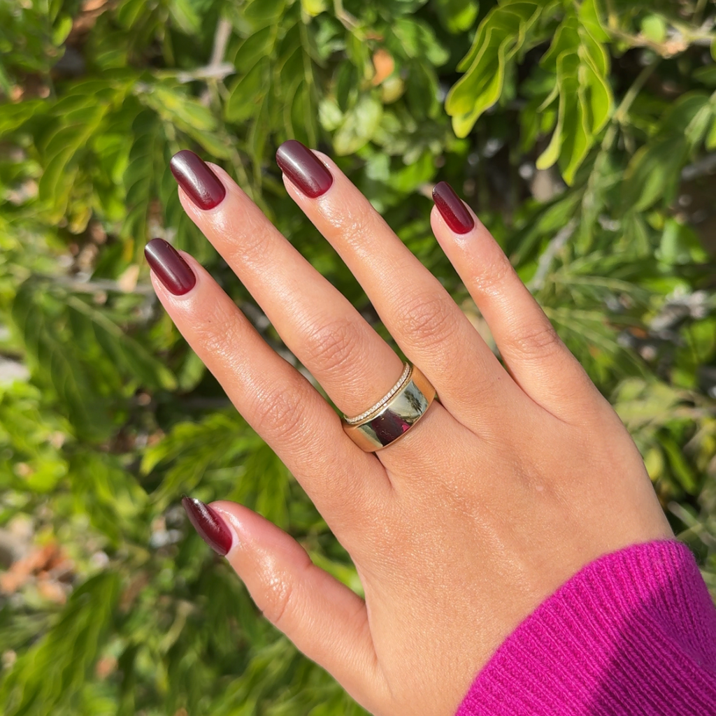 Vineyard | Short | Round - Tab Press-On showing hand with deep wine red glossy false nails and silver ring outdoors in sunlight