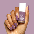 Hand holding Cardigan quick dry gel polish bottle showing matching mauve manicure on medium-length nails on mauve background