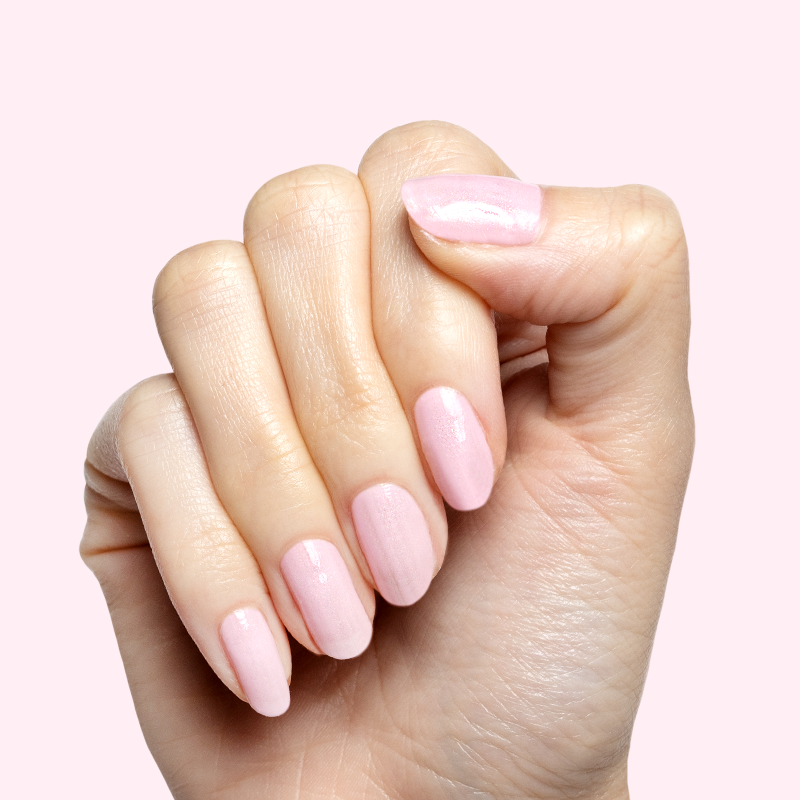 Hand with short nails painted in Crown shimmery princess pink gel polish showing a smooth at home manicure