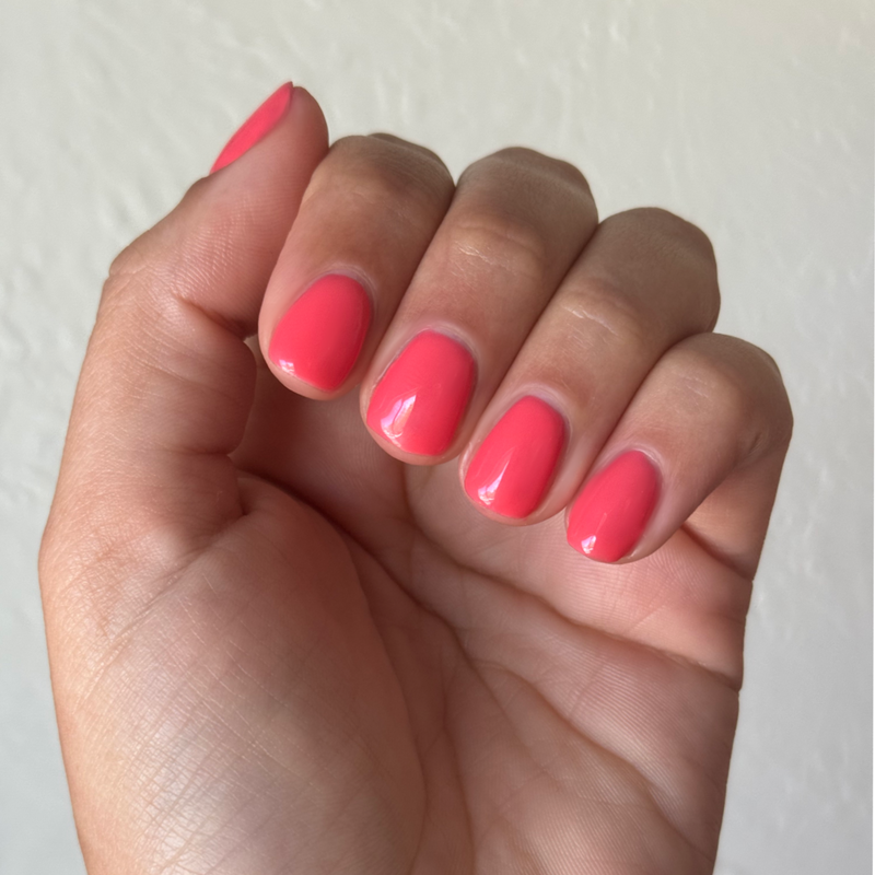 Hand with short rounded nails painted in glossy juicy watermelon red using Field Day - Gel polish
