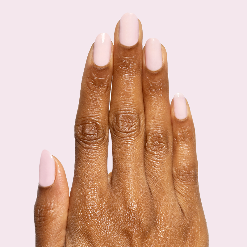 Hand with Glossed sheer lavender-pink gel polish manicure with glossy finish on natural nails against pale pink background