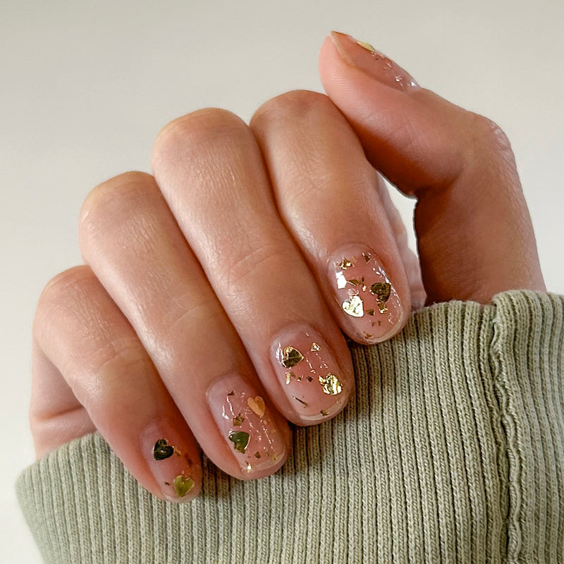 Valentine Mini Polish Set nails with nude base and gold heart-shaped sequins for a subtle at-home manicure look