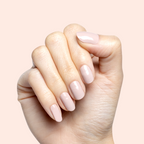 Hand with short nails painted in Kitten neutral greige polish showing a clean, polished at home manicure look