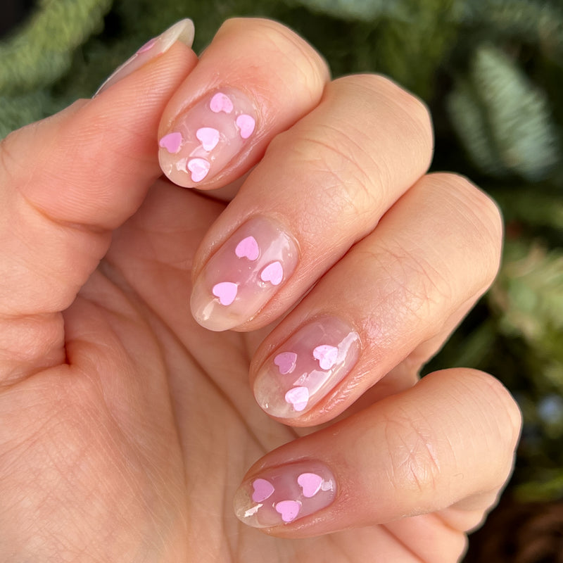 Valentine Mini Polish Set nails with clear polish and scattered soft pink heart sequins for a simple mani look