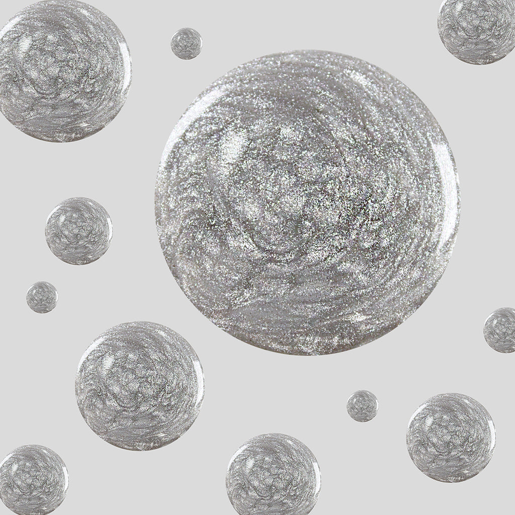 Glossy silver glitter polish droplets in Midnight Disco showing ultrafine shimmer on a neutral gray background