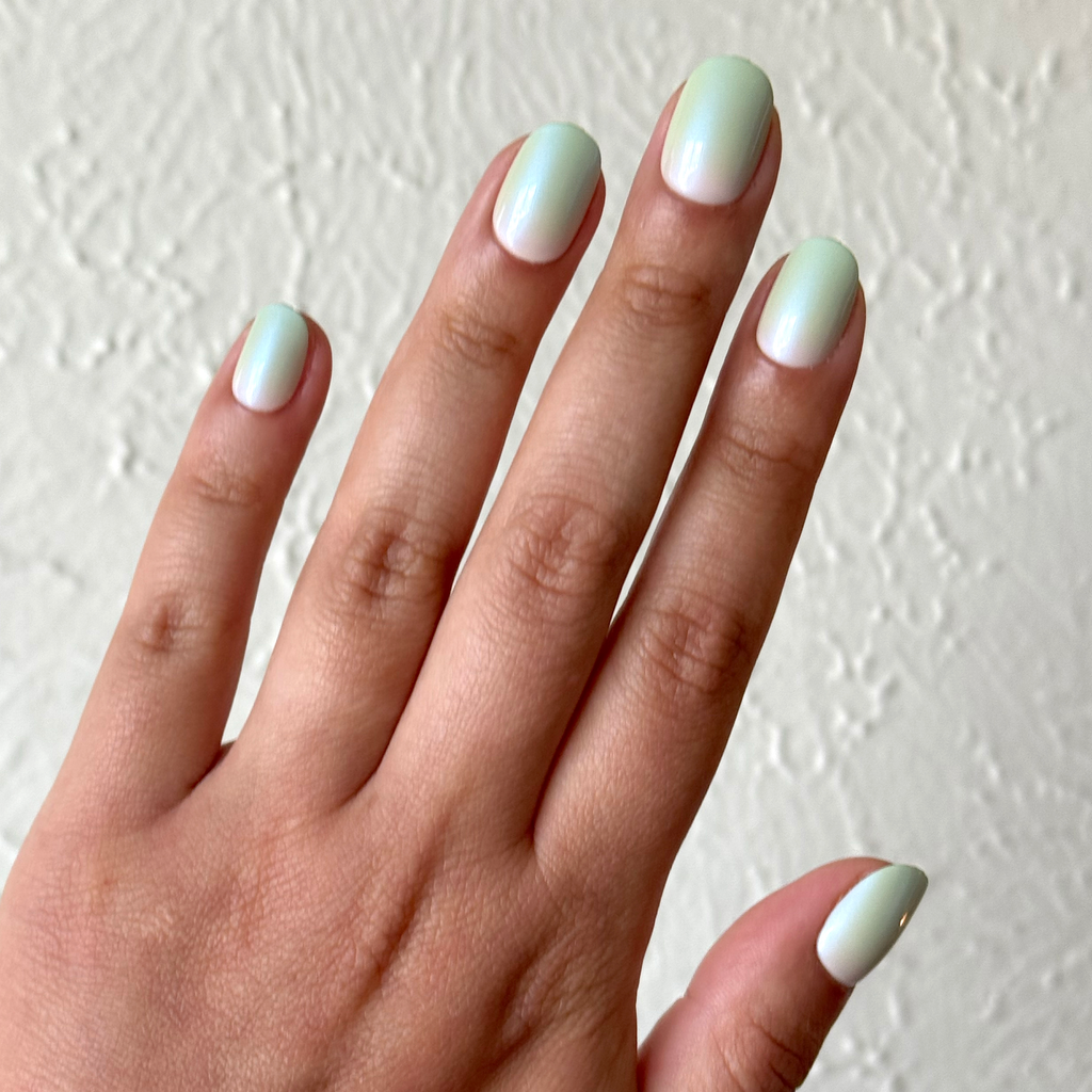 Hand displaying Minty Shimmer | Extra Short | Round - Tab Press-On nails in soft mint gradient with delicate shimmer finish