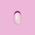 Plum Tonal French - Press-On | Short | Round showing single short round false nail with plum French tip on pink background