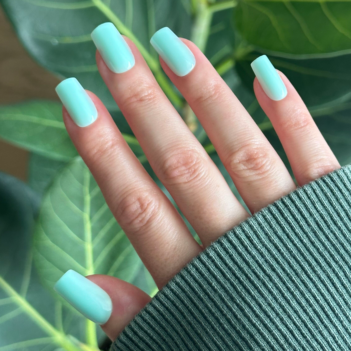 Slam Dunk - Press-On | Medium | Square turquoise false nails shown on hand with green leafy background for at-home mani