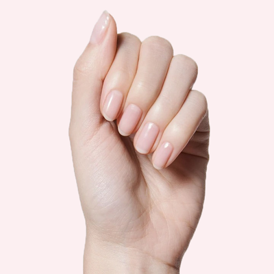Hand holding a bottle of CCT sheer neutral pastel pink polish with natural nails for a soft manicure look CCT sheer pink Nail Polish