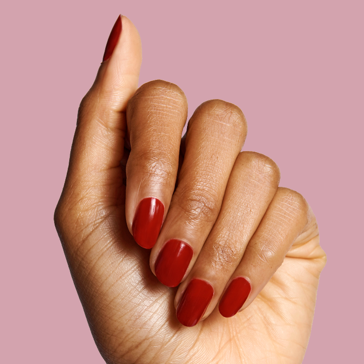 Hand showing smooth mani with SC deep bordeaux polish on medium skin tone against light mauve background