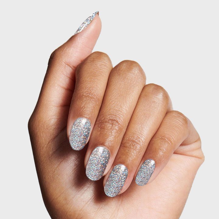 Hand showing nails painted with Exclamation Point silver holographic glitter polish for a sparkling at-home mani