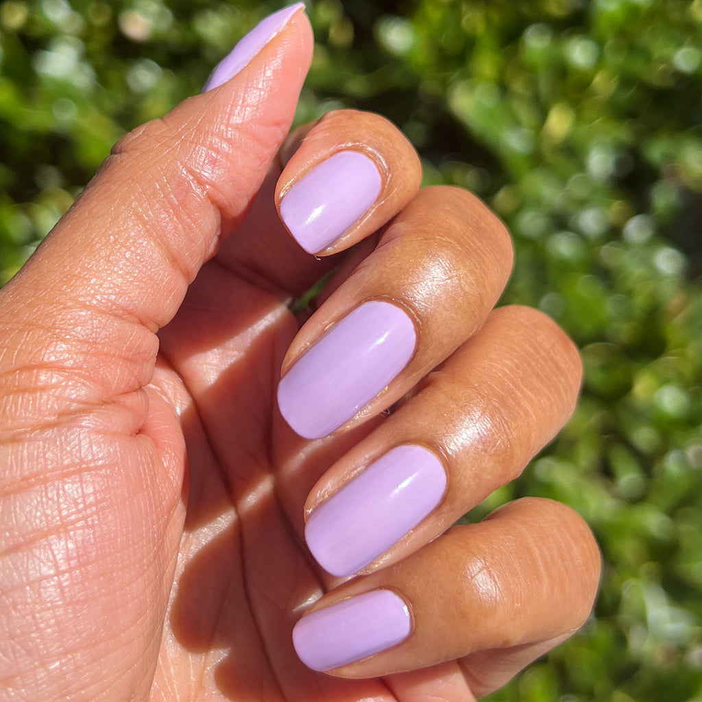 Hand with nails coated in You're Invited lilac gel polish by Olive and June for a smooth, durable manicure finish