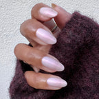 Hand featuring almond-shaped nails painted with Pink Capiz long-lasting polish in soft iridescent pink shade