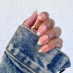 Hand with natural nails polished in Crystal clear coat holding a denim jacket sleeve showing a glossy manicure
