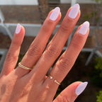 Hand with nails painted in soft white Swan polish showcasing a polished quick dry manicure in natural light