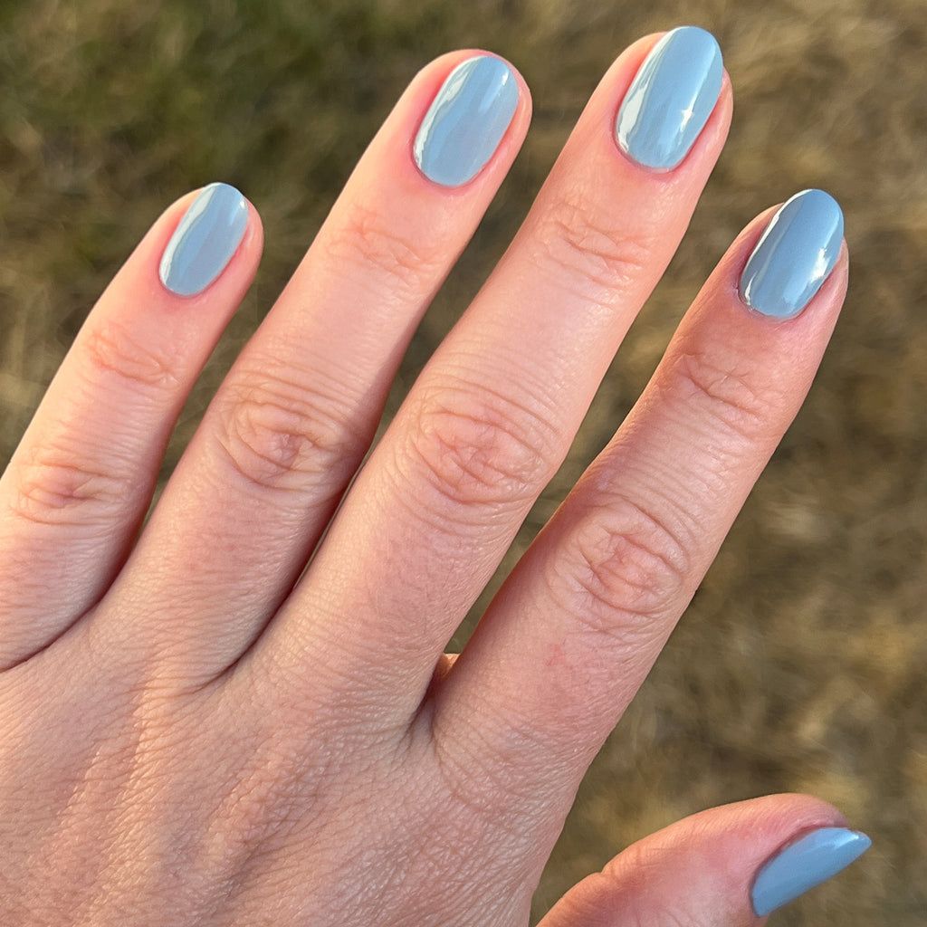 Hand with nails painted in Vintage denim blue showing a smooth, quick dry manicure by Olive and June
