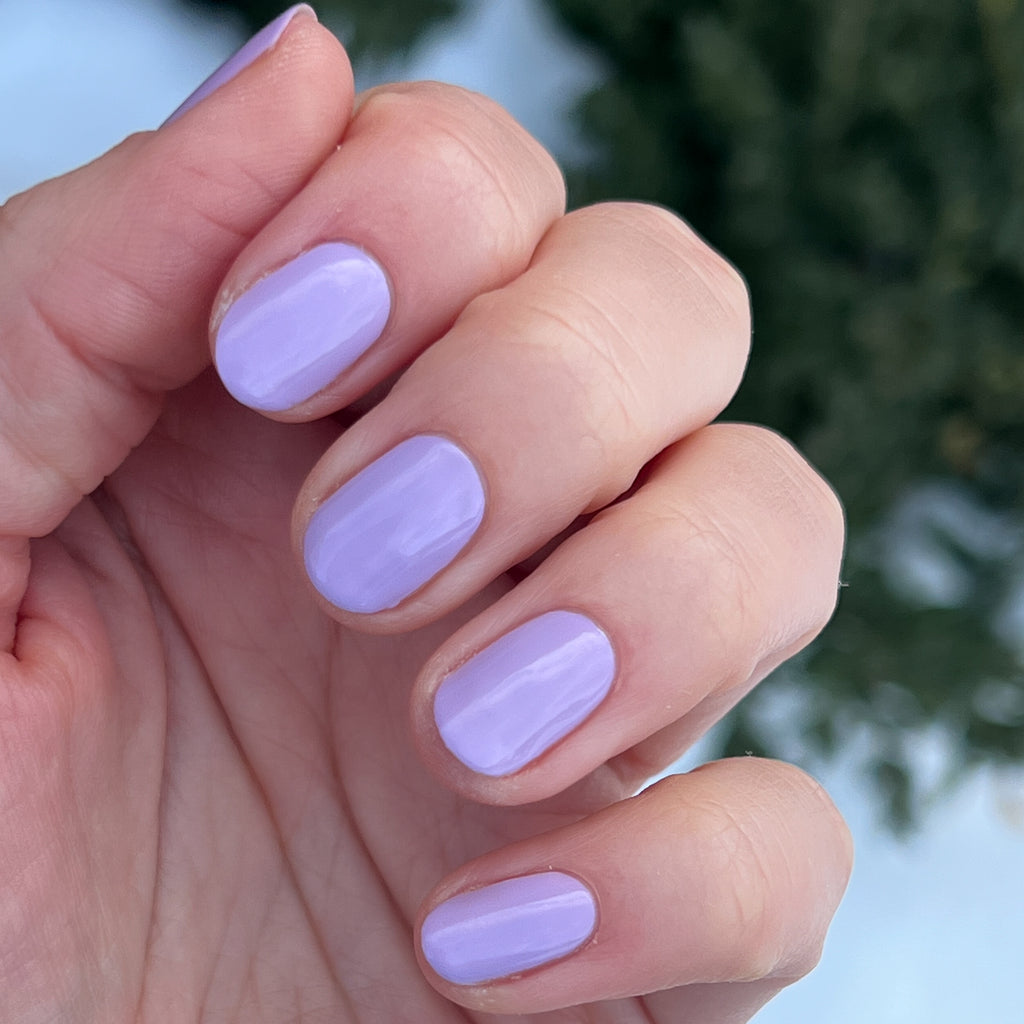 Hand with nails painted in glossy lilac shade of You're Invited gel polish for smooth, long-lasting manicure by Olive and June
