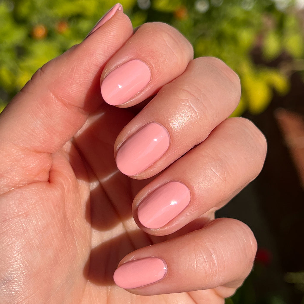 Hand with medium-length nails painted in Nuance bubblegum pink polish for a glossy at-home manicure look