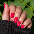 Hand displaying smooth nails painted with XOXO hot pink polish for a bright, long-lasting manicure outdoors