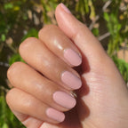 Hand with nails in Poodle neutral beigey pink polish for a smooth and polished at-home manicure look