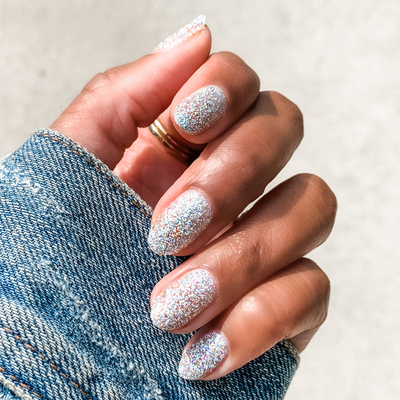 Hand with nails covered in Olive and June Exclamation Point silver holographic glitter polish for a sparkling manicure