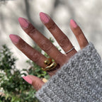 Hand with oval-shaped nails painted in Nuance medium bubblegum pink for a smooth and polished manicure look